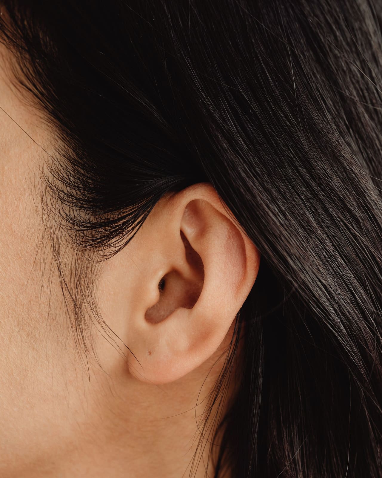 Orelha em close, com o cabelo preso atrás